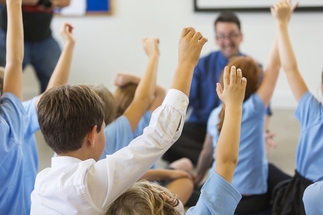 alunos com a mão levantada em sala de aula